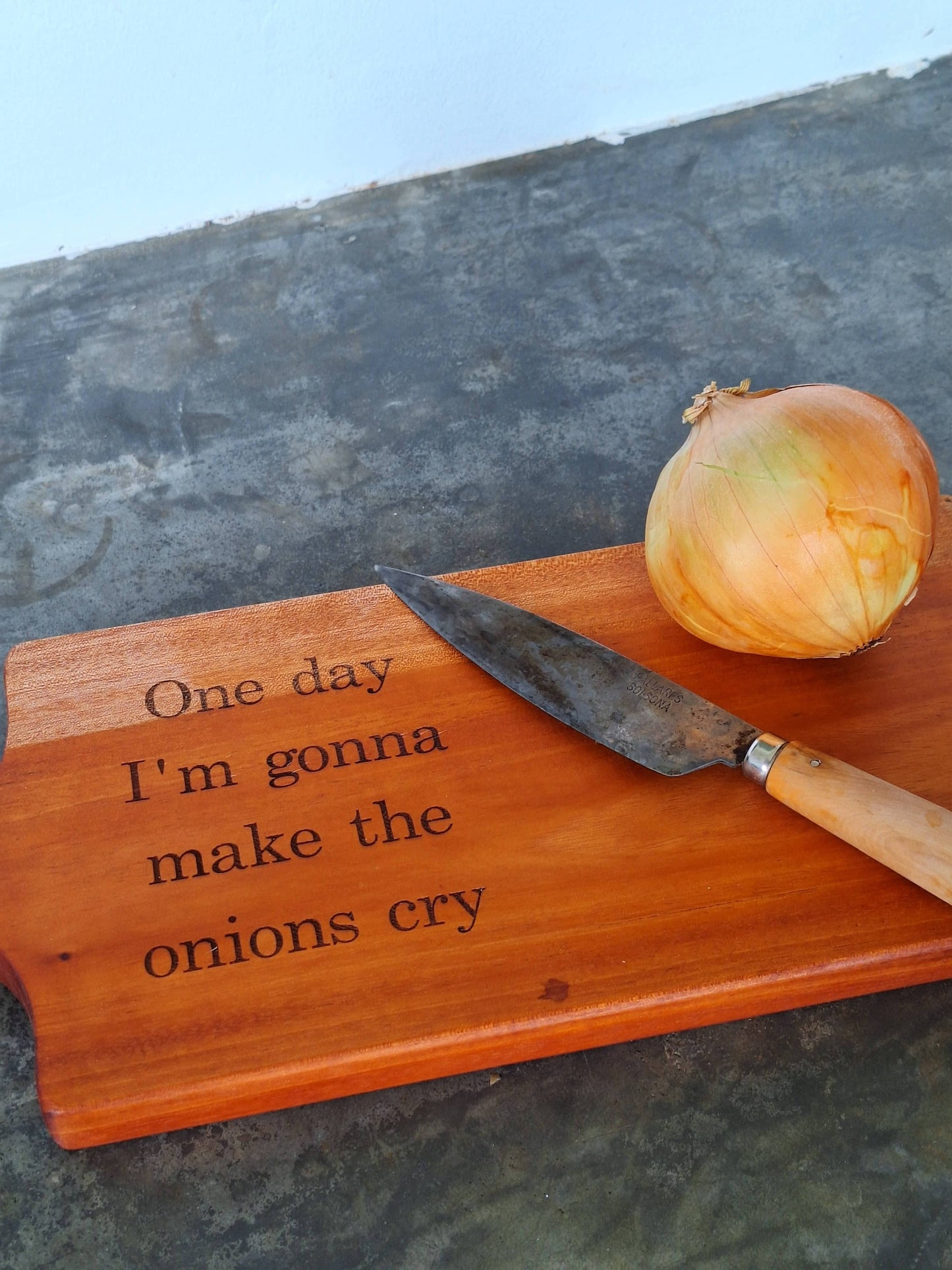 Cutting board displayed with a knife and an onion