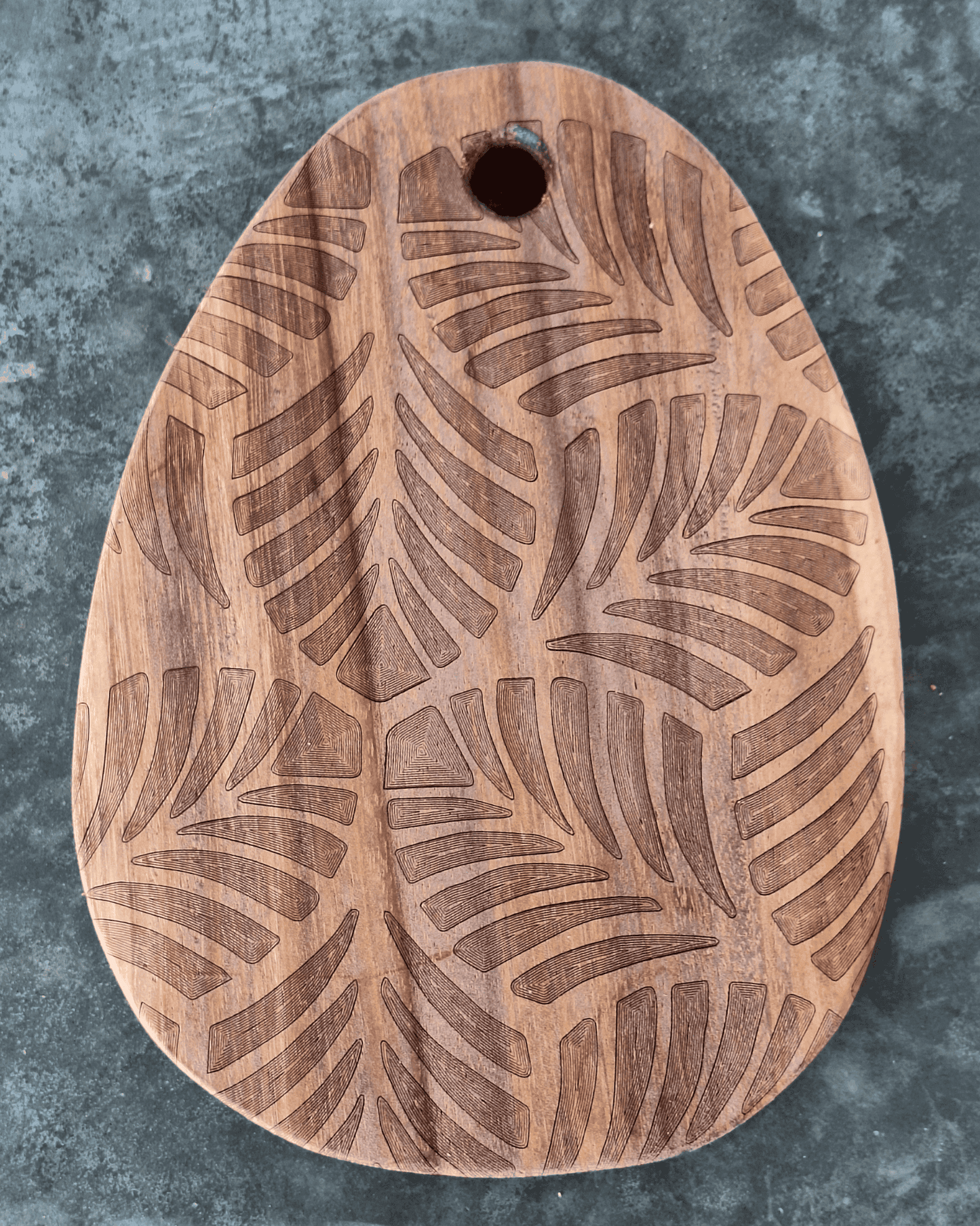 Tiny egg shaped cutting board with tropical leaves engraved