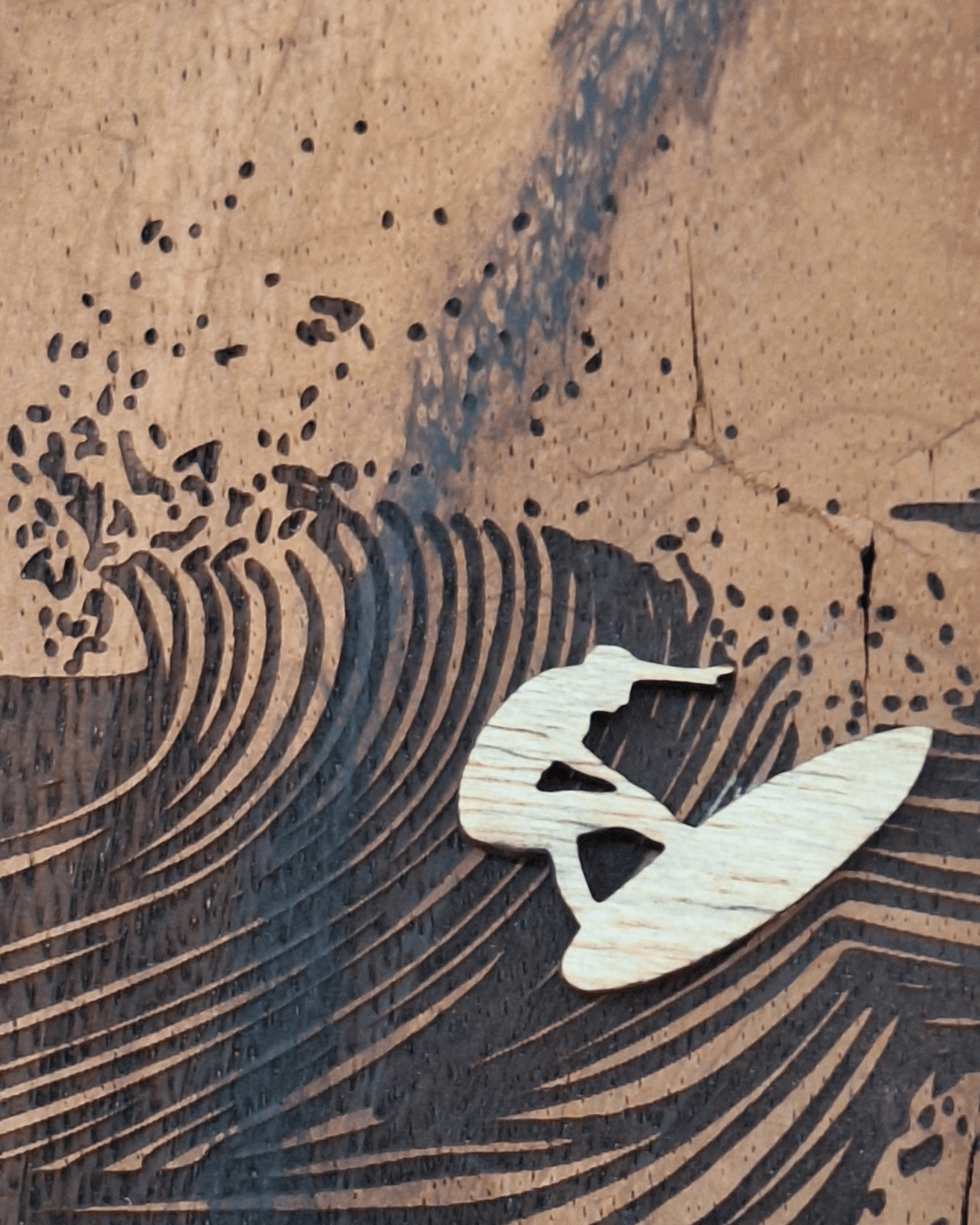 detail of the laser engraving and the wooden surfer