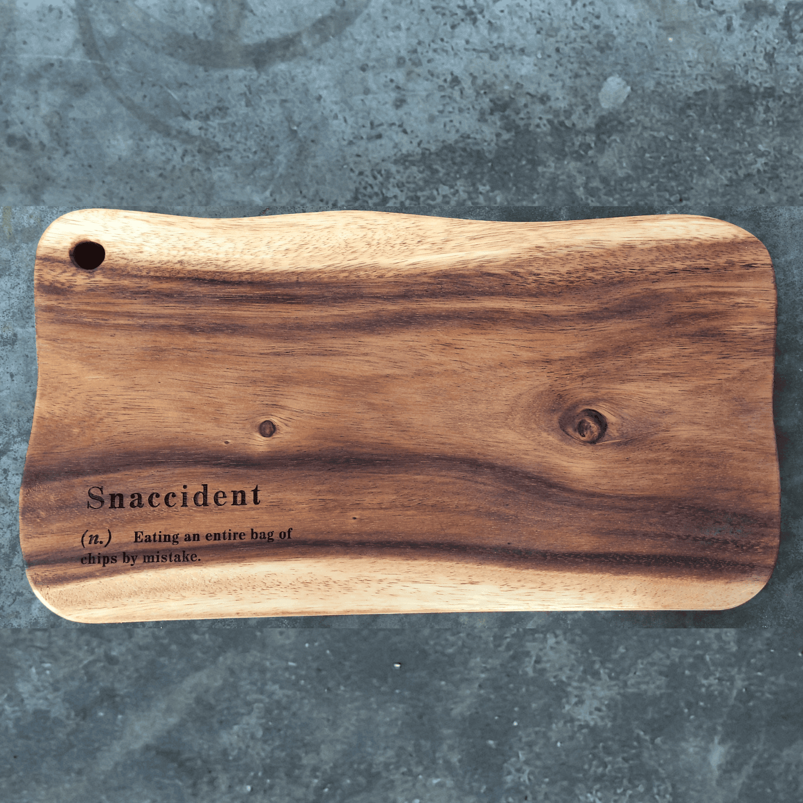 Wooden cutting board with the humor definition of "snaccident"