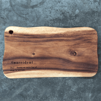 Wooden cutting board with the humor definition of "snaccident"