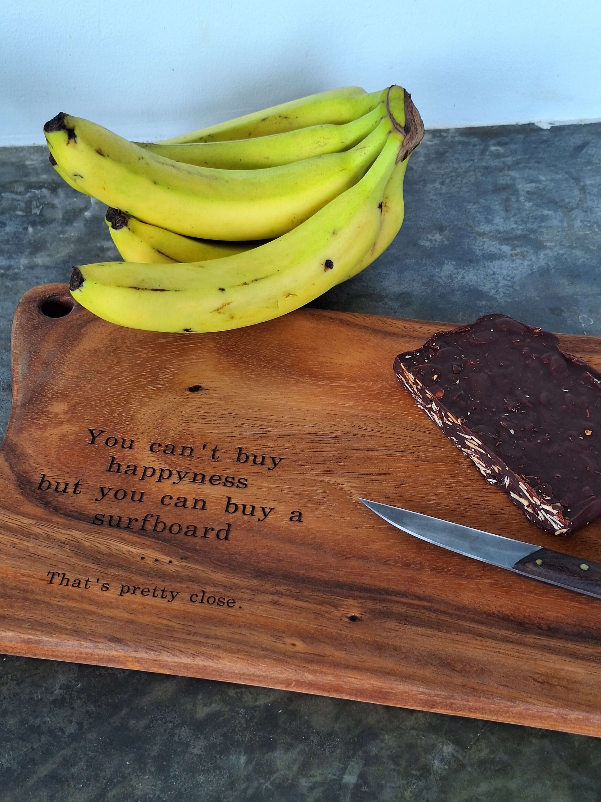Wooden cutting board displayed with bananas and almond dark chocolate